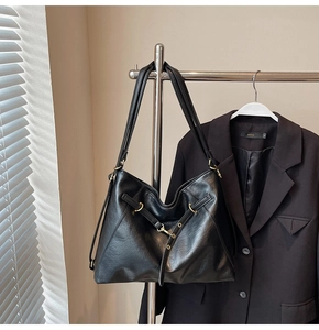 Detail of black leather tote bag showing soft texture and golden metal buckle accents