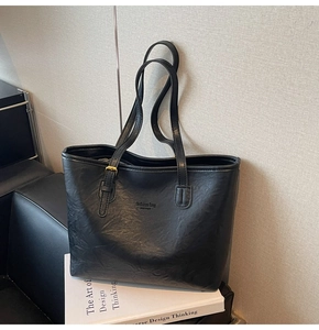 Macro shot of black tote bag featuring matte leather texture and gold buckle detail