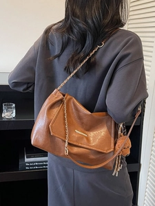 Brown leather underarm bag with gold chain strap and teddy bear charm accessory