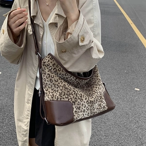 Detailed close-up of leopard print canvas and brown leather trim on a crossbody bag