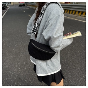 Detail view of black corduroy saddle bag featuring a stylish black and white geometric strap