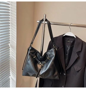Detailed shot of a black slouchy tote bag featuring adjustable straps and gold metal hardware