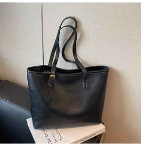 Close-up of black leather tote bag featuring litchi texture and gold metal hardware