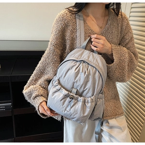 Detail of grey crinkled nylon backpack showing drawstring pocket and matte texture