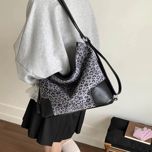 Grey leopard print tote bag with leather trim worn over the shoulder for daily commute