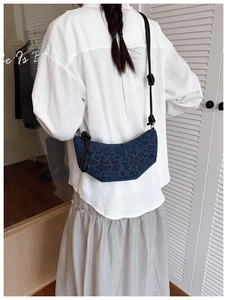 Macro detail of navy denim crescent bag featuring black leopard print and knot strap