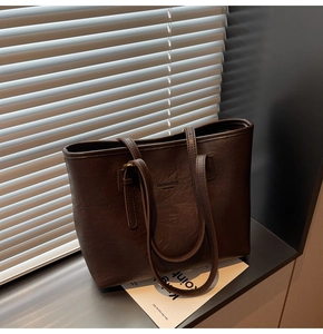 Detailed view of dark brown tote bag with embossed logo and textured faux leather finish
