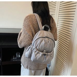 Detail of grey quilted nylon backpack with drawstring pocket and double zipper closure