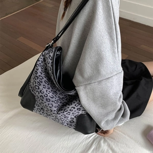 Detail of leopard print tote bag with black leather reinforcement and side stitching