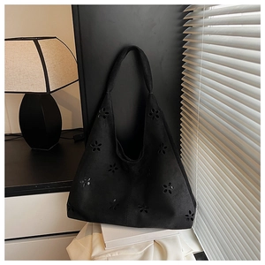 Detailed view of black laser-cut floral pattern on a soft suede tote shoulder bag