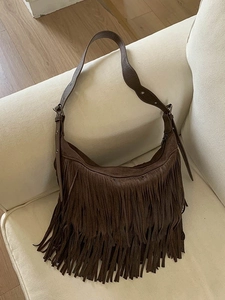 Borsa a tracolla in pelle scamosciata marrone con nappe bohémien su divano bianco