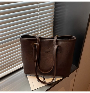 Detailed macro view of dark brown PU leather tote with a textured finish and embossed text