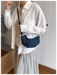 Detail of denim leopard print crescent bag with distinctive knotted shoulder strap style