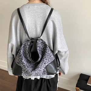 Rear view of model wearing a stylish leopard print backpack with black leather trim
