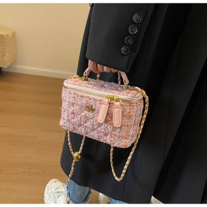 Detail of pink tweed shoulder bag with golden floral accents and chain strap