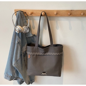 Detailed embroidery of cartoon character and Doolle-girl text on dark grey canvas tote bag
