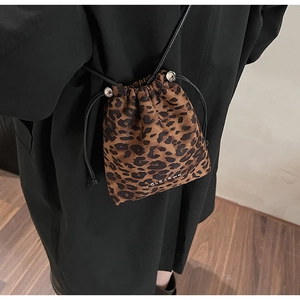 Détail d'un sac seau léopard avec cordon de serrage et décoration logo métallique