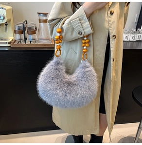 Sac croissant en fausse fourrure grise avec perles en bois orange sur une tenue élégante