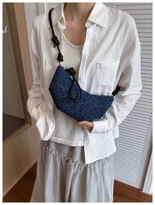 Detail of blue leopard denim croissant bag with knotted leather strap on shoulder