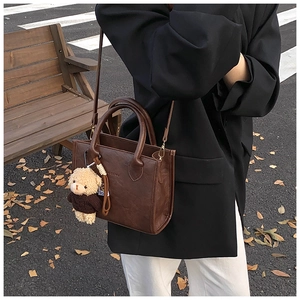 Brown vintage faux leather crossbody bag detail with cute teddy bear charm on model
