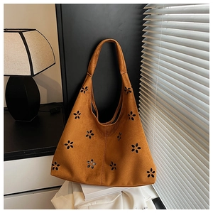 Close-up of brown suede hobo bag with vintage laser-cut floral patterns and soft texture