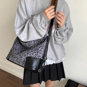 Detail of grey leopard print tote bag with black PU leather straps on a model
