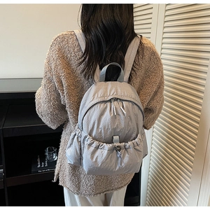 Close-up of lightweight grey nylon backpack with drawstring pockets shown on model back