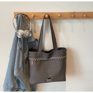 Detail of dark grey canvas tote bag featuring wave embroidery and cartoon boy print
