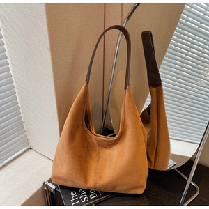 Detail view of brown suede hobo bag with leather handles shown in a mirror reflection