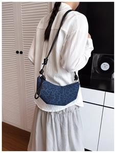 Detailed view of leopard print crescent bag in blue denim with knotted strap accents