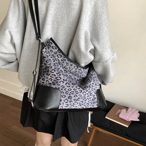 Detail view of large leopard print tote bag with black leather patchwork on model