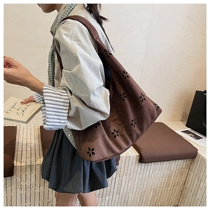 Detail of dark brown suede hobo bag featuring laser-cut floral patterns and wide strap