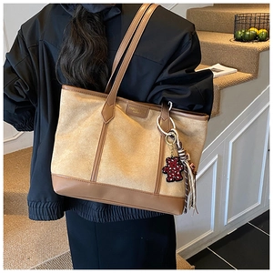 Dettaglio di una grande borsa tote in pelle scamosciata marrone con ciondolo a forma di orso