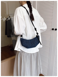 Close-up of leopard print denim crescent bag with knotted rope shoulder strap detail