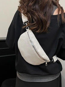 Minimalist beige corduroy crossbody saddle bag with a patterned wide strap on a model