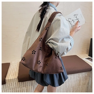 Detail view of coffee brown suede hobo bag with floral cutouts and wide shoulder strap