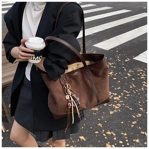 Detail of a brown suede tote bag with decorative tassel and leather handle for commuting