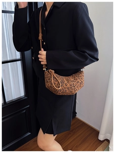 Detail of leopard print crescent bag featuring brown animal pattern and knotted strap
