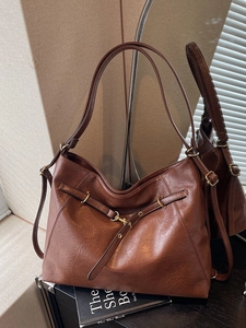 Brown leather tote bag with vintage texture and golden metal hooks in an elegant studio shot
