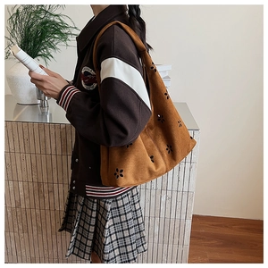 Detailed side view of brown suede underarm bag with unique laser-cut floral patterns