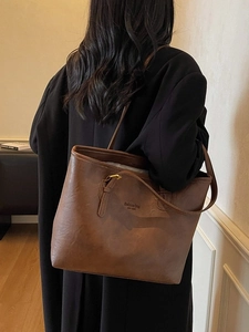 Chic dark brown faux leather tote bag with long handles shown on a model's shoulder