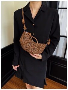 Detailed view of leopard print hobo bag with knotted cord strap on model in black suit