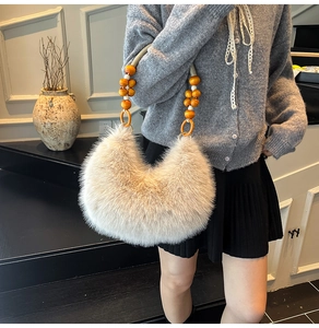 Détail d'un sac à bandoulière en fausse fourrure crème avec poignée décorative en perles