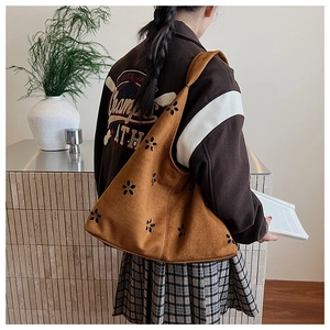 Detailed laser-cut floral pattern on brown suede asymmetrical shoulder bag