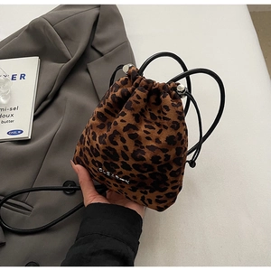Détail du sac seau léopard avec cordon de serrage, logo argenté et texture en peluche
