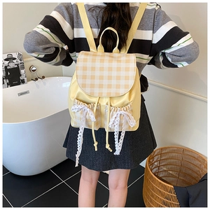 Detail of yellow plaid backpack with lace bows and drawstring pockets on model
