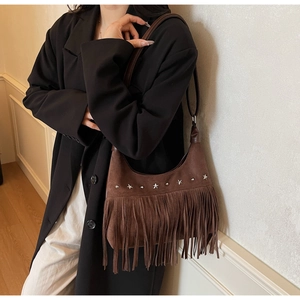 Dettaglio della borsa in pelle scamosciata marrone con frange e borchie a stella