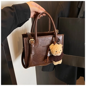 Close-up of vintage brown leather handbag with HOGOMU logo and cute bear charm