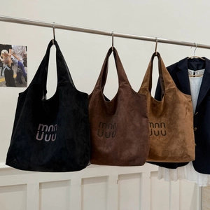 Detailed view of suede tote bags showing soft texture and premium logo in multiple colors