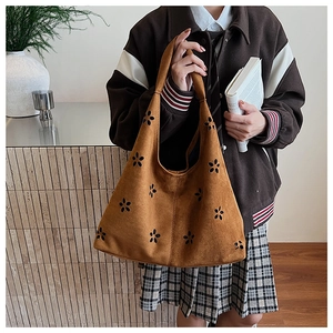 Detailed laser-cut flower patterns on brown suede tote bag in a casual setting
